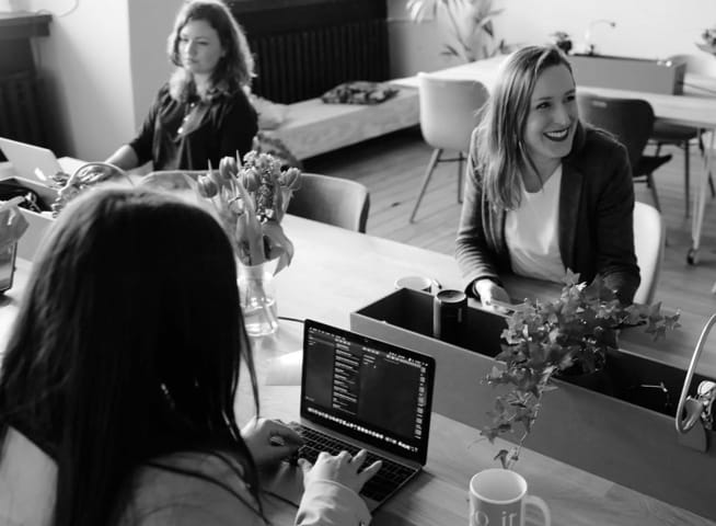 Three womens working on laptops at the desk in the office.